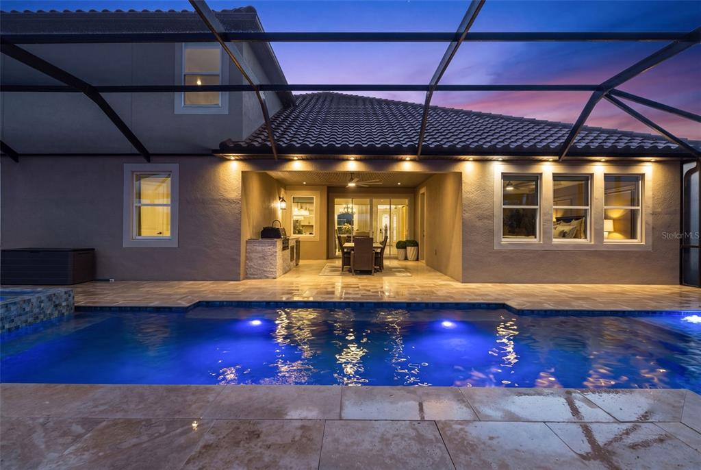 A swimming pool sits in front of a covered patio with an outdoor kitchen and dining area — 33161 KATELAND DRIVE, WESLEY CHAPEL, FL