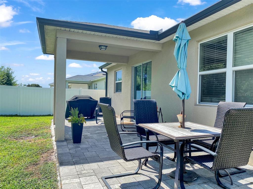 A paved patio features a dining set with a blue umbrella and a covered grill — 4548 ORCHARD GROVE ROAD, ST CLOUD, FL