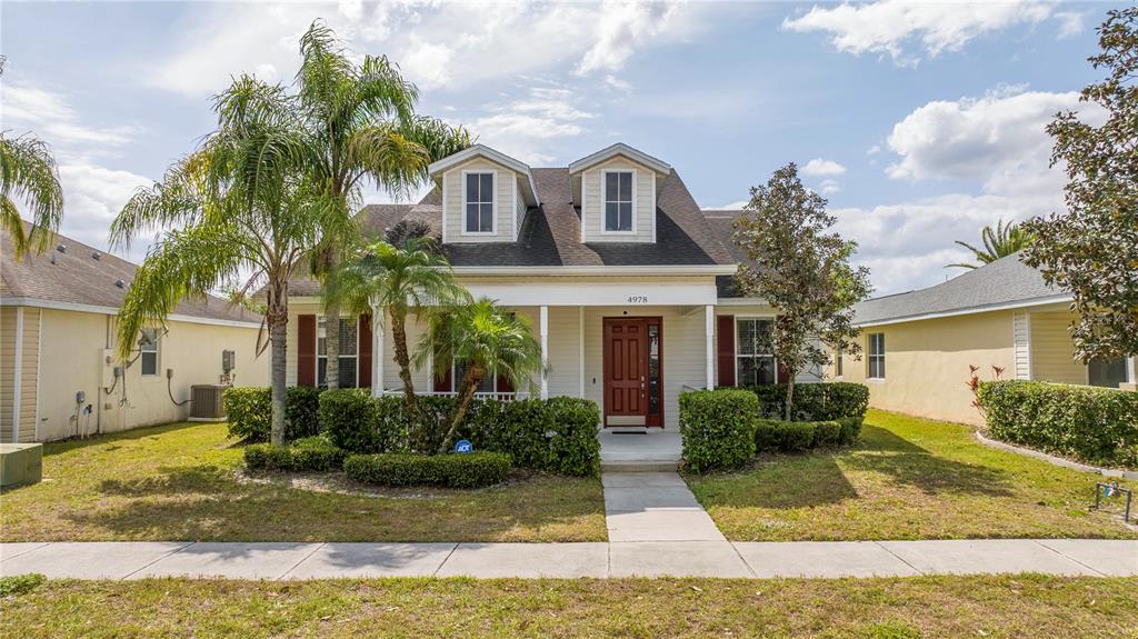 A two-story house with a front porch, dormer windows, and a palm tree in front — 4978 STRAND STREET UNIT 0, KISSIMMEE, FL