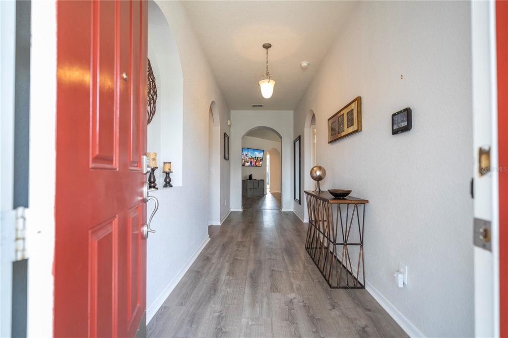 A view from an open red front door into a hallway with wood-look flooring — 4978 STRAND STREET UNIT 0, KISSIMMEE, FL