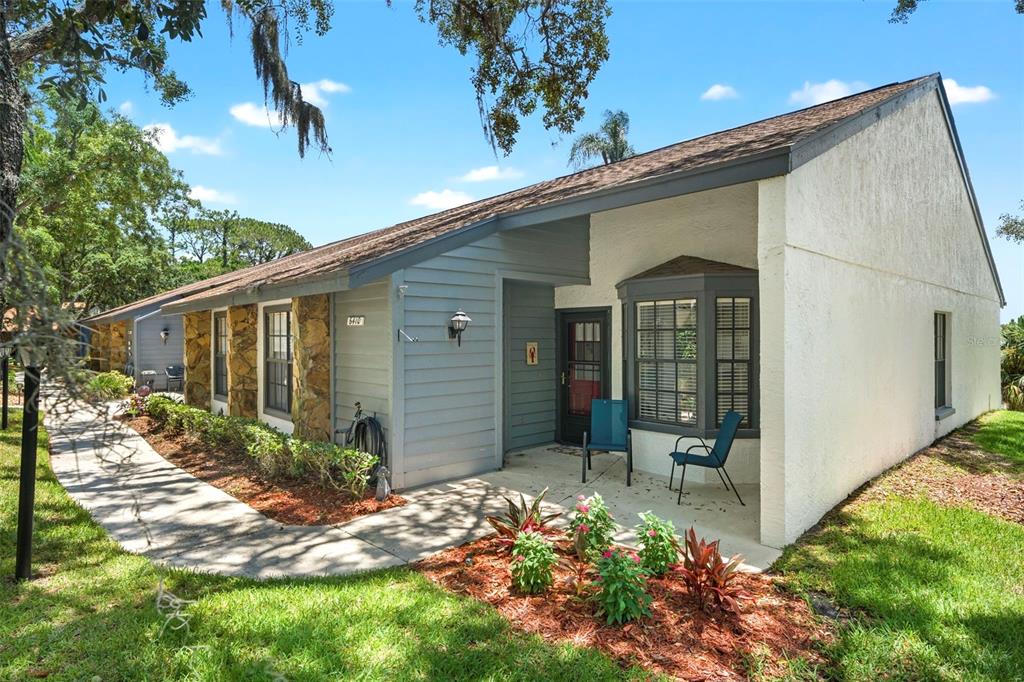 A single-story house with a stone facade, blue siding, and a covered front patio — 6410 NATURE PRESERVE LANE, SPRING HILL, FL