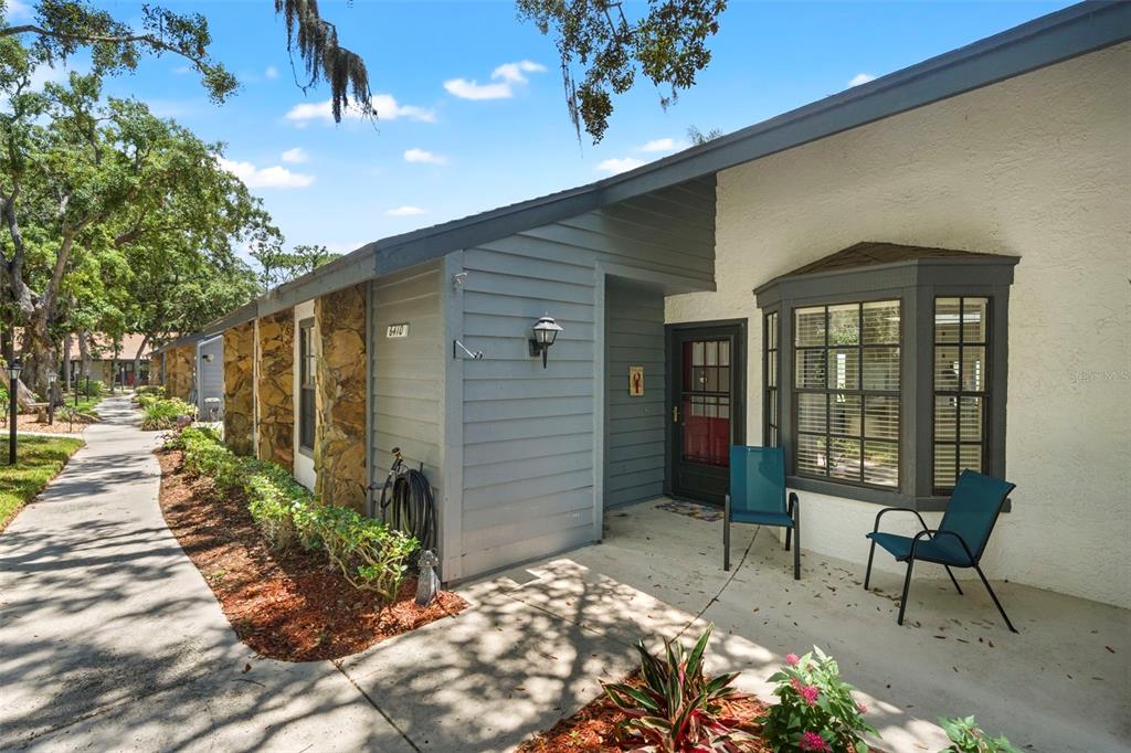 A single-story home exterior features a stone facade, gray siding, and a front patio area — 6410 NATURE PRESERVE LANE, SPRING HILL, FL