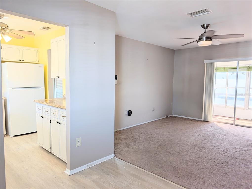 A kitchen with white cabinets and a carpeted living area with a ceiling fan — 1830 SUNNY DRIVE UNIT D31, BRADENTON, FL