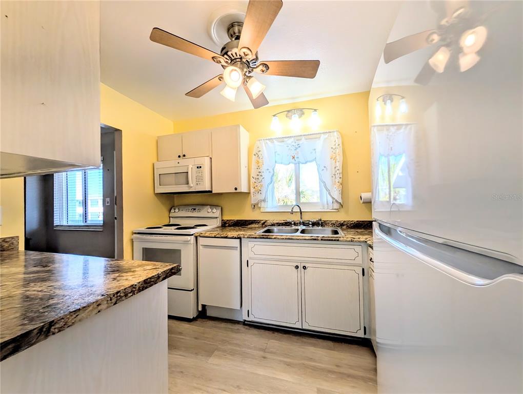 A kitchen with white cabinets, yellow walls, a ceiling fan, and a white refrigerator — 1830 SUNNY DRIVE UNIT D31, BRADENTON, FL
