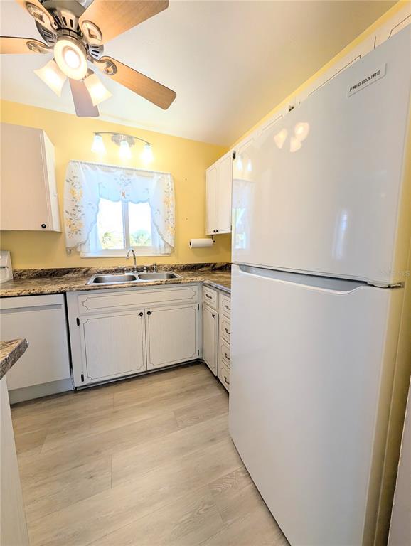 A kitchen features white cabinets, a Frigidaire refrigerator, a double sink, and light wood flooring — 1830 SUNNY DRIVE UNIT D31, BRADENTON, FL
