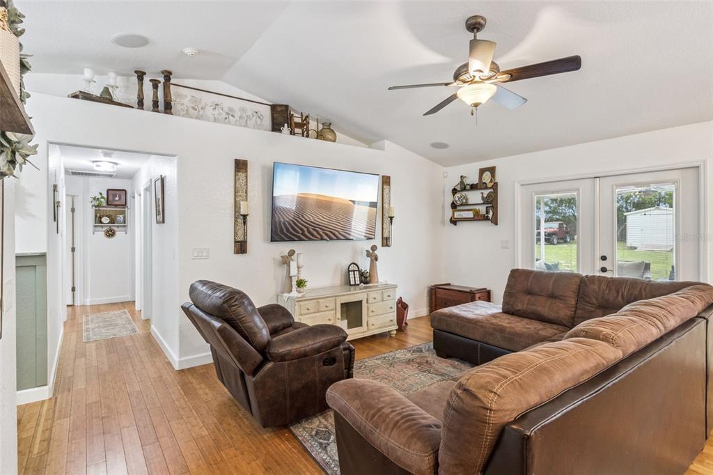 A living room features brown leather furniture, a wall-mounted television, and wood flooring — 214 MOUNTAIN DRIVE, BABSON PARK, FL