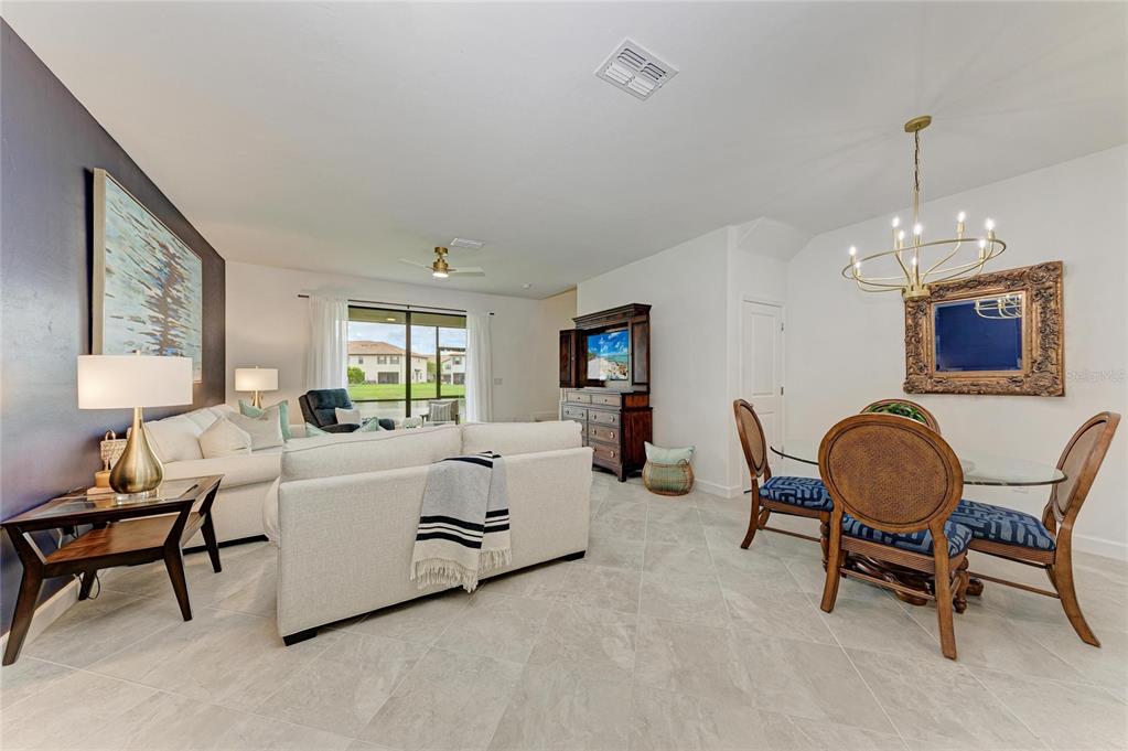An open-concept living and dining area features tile flooring, a white sofa, and a chandelier — 14767 LYLA TERRACE, LAKEWOOD RANCH, FL