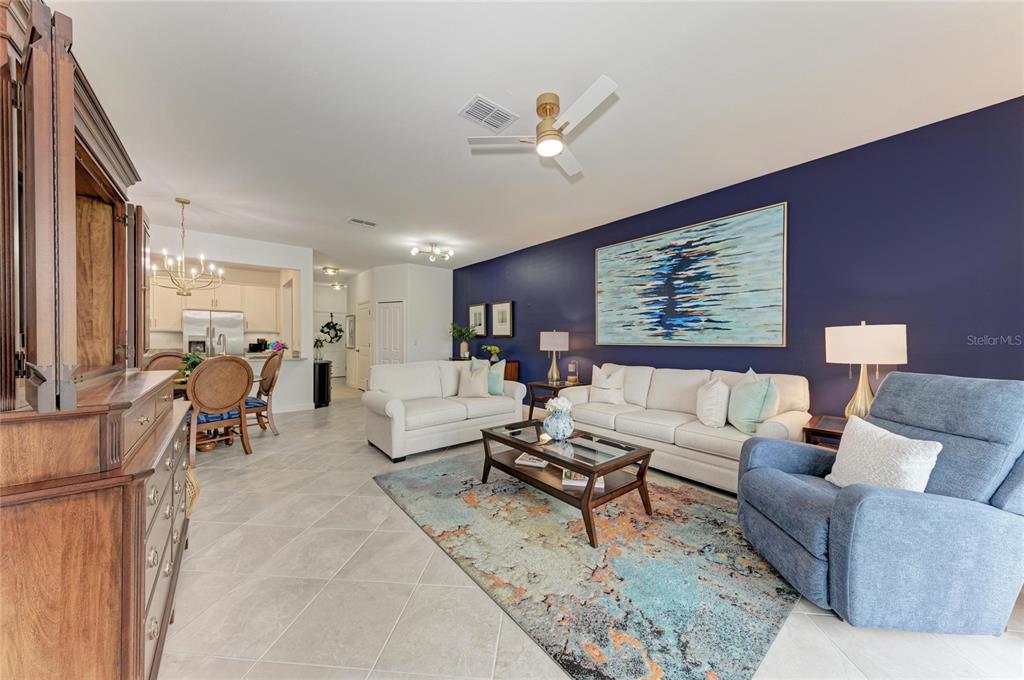 A living room features a dark blue accent wall, white sofas, and a patterned area rug — 14767 LYLA TERRACE, LAKEWOOD RANCH, FL