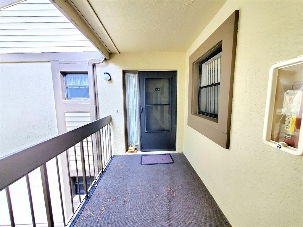 An outdoor apartment balcony features a dark screen door, a window, and a fire extinguisher — 20 WOODLAKE PLACE UNIT 20, OLDSMAR, FL