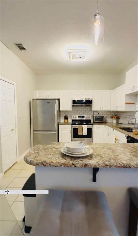 A kitchen features white cabinets, stainless steel appliances, and a granite-topped breakfast bar — 3107 SUN LAKE COURT UNIT B, KISSIMMEE, FL