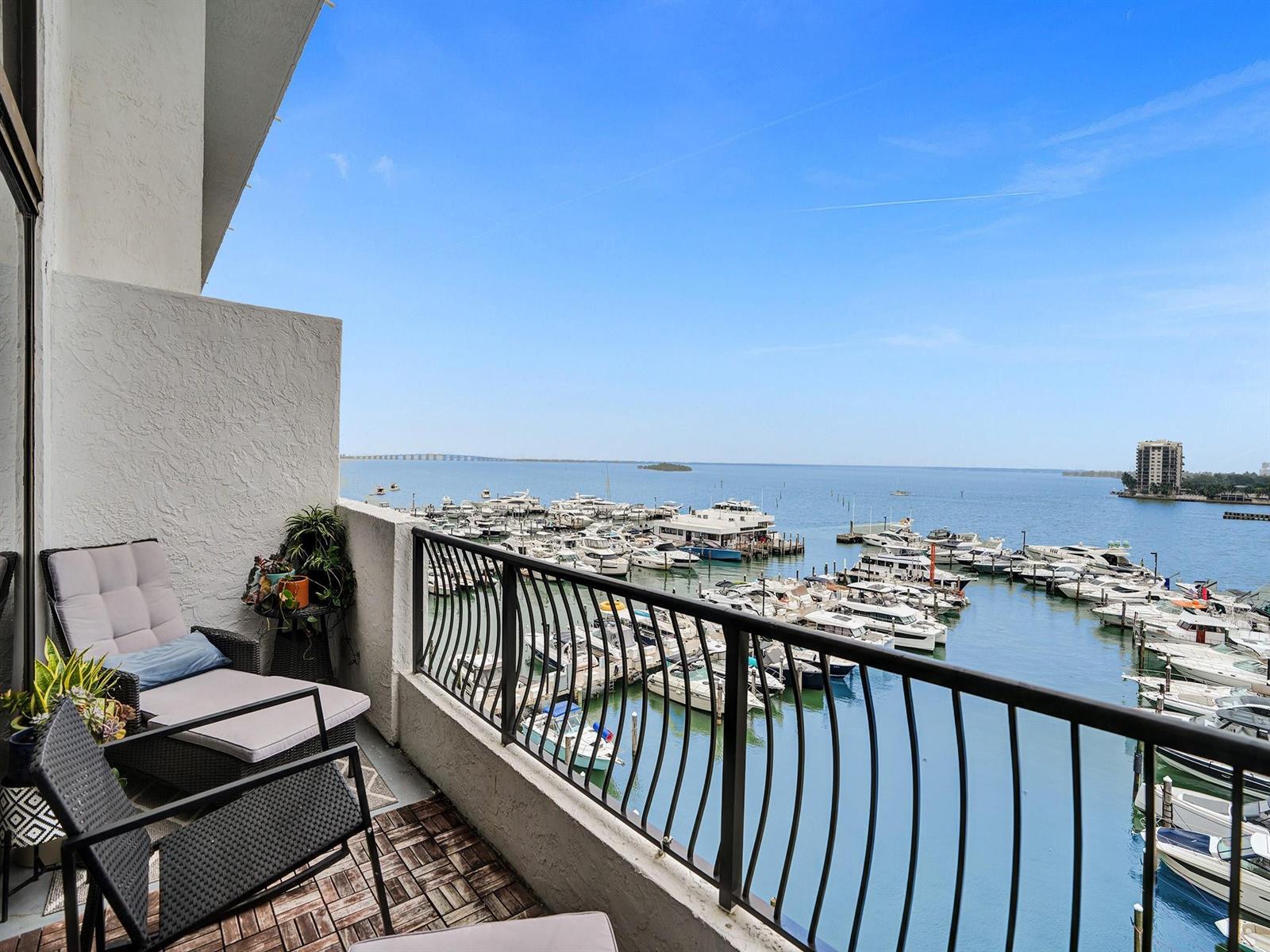 A balcony with patio furniture overlooks a marina filled with boats on a sunny day — 555 NE 15th Street, Miami FL 33132, MIAMI, FL