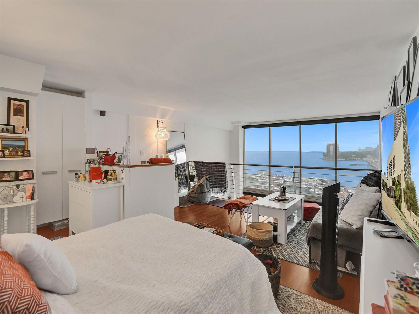 A bedroom with a bed, seating area, and floor-to-ceiling windows overlooking a marina and bay — 555 NE 15th Street, Miami FL 33132, MIAMI, FL