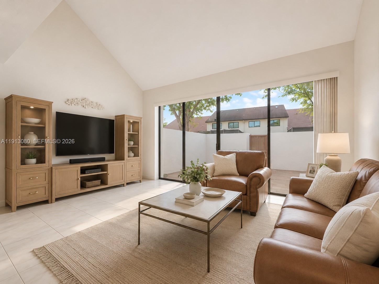A living room features light tile floors, vaulted ceilings, leather furniture, and large sliding glass doors — 13350 SW 91st Ter # C, Miami FL 33186, MIAMI, FL