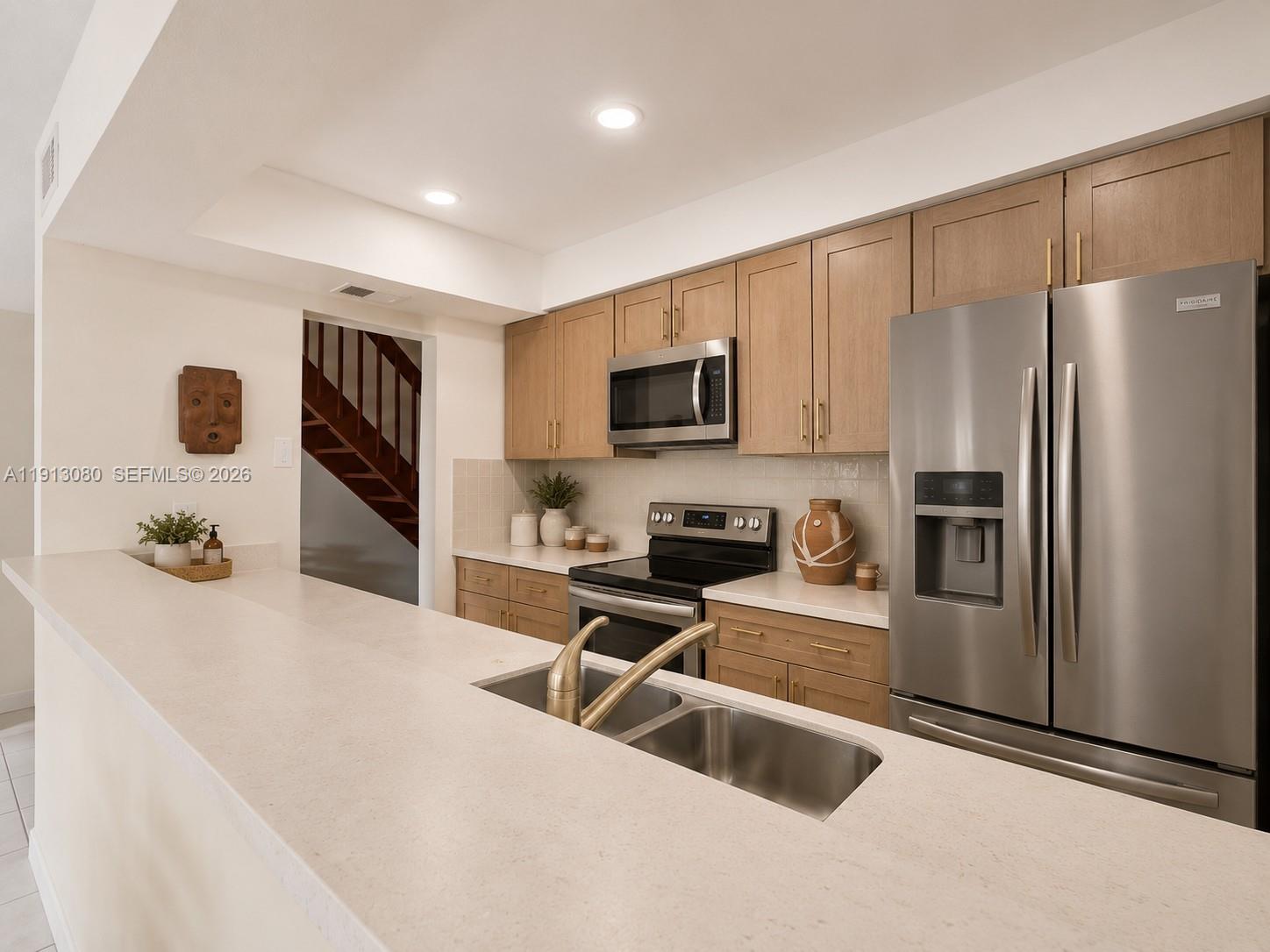 A kitchen features light wood cabinets, stainless steel appliances, and a white countertop island — 13350 SW 91st Ter # C, Miami FL 33186, MIAMI, FL