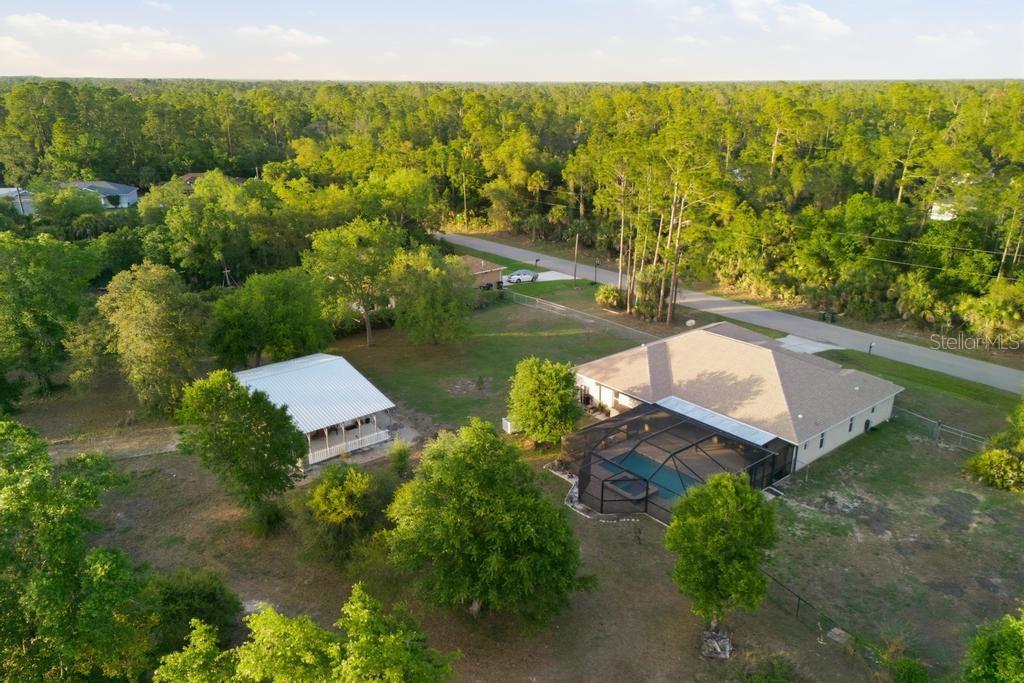 An aerial view shows a house with a pool enclosure and a detached metal building — 2105 BENNETT LANE, NORTH PORT, FL