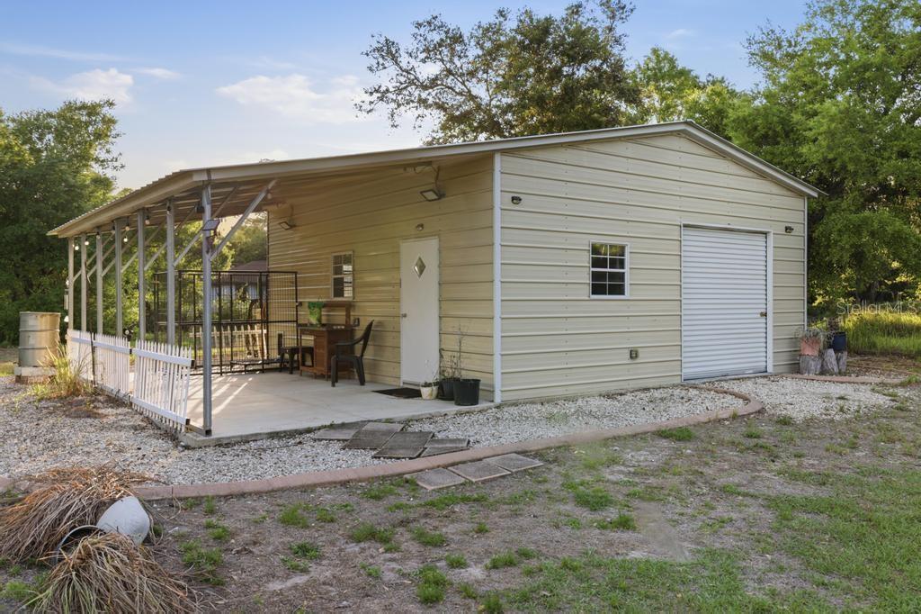A metal workshop building with an attached carport, a roll-up door, and a side entrance — 2105 BENNETT LANE, NORTH PORT, FL
