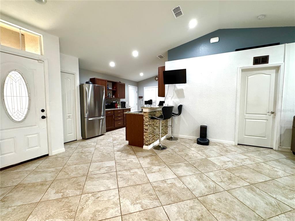 A kitchen with a stone-accented breakfast bar, stainless steel refrigerator, and tiled flooring — 248 CHICAGO AVENUE W, HAINES CITY, FL