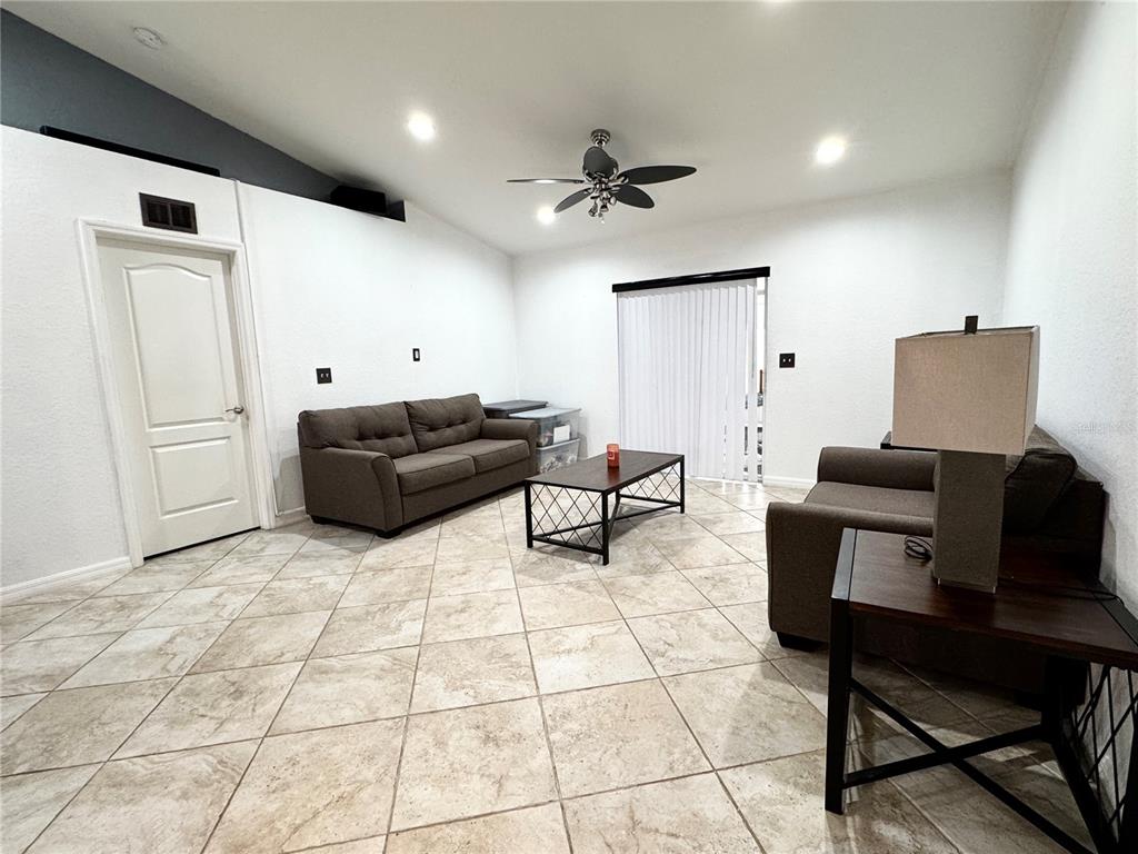 A living room features tile flooring, two brown sofas, a coffee table, and a ceiling fan — 248 CHICAGO AVENUE W, HAINES CITY, FL