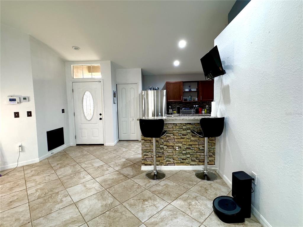 A kitchen with a stone-accented breakfast bar, tile flooring, and an adjacent entryway — 248 CHICAGO AVENUE W, HAINES CITY, FL