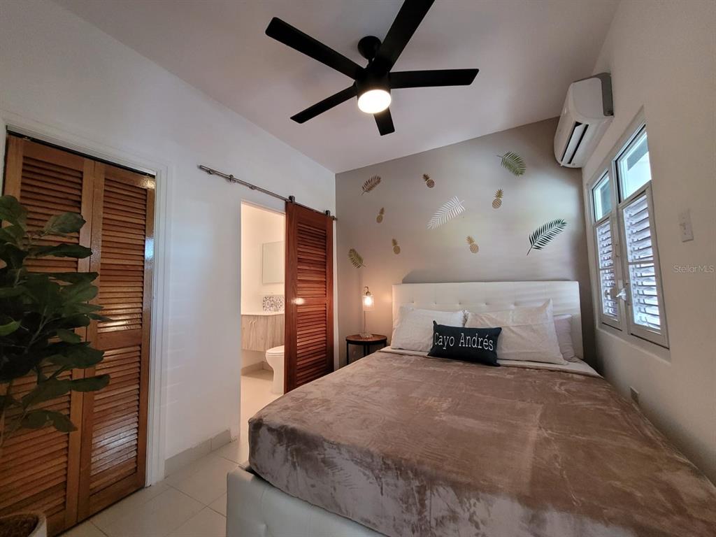 A bedroom features a bed with a brown blanket, a ceiling fan, and tropical wall decals — 2301 SOLDADO CRUZ, SAN JUAN, PR