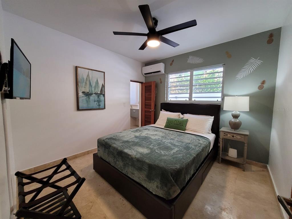 A bedroom features a bed with a green blanket, a ceiling fan, and a wall painting — 2301 SOLDADO CRUZ, SAN JUAN, PR