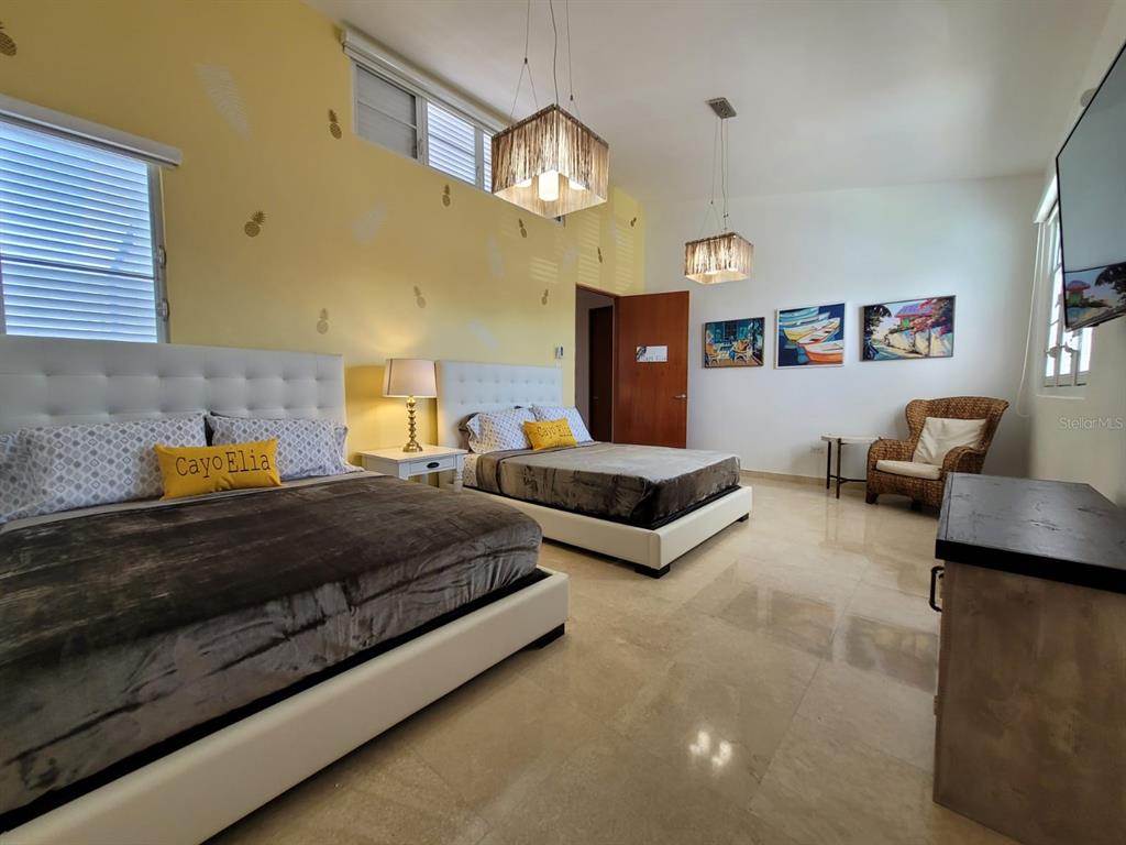 A bedroom features two beds, yellow walls with pineapple decals, and two hanging light fixtures — 2301 SOLDADO CRUZ, SAN JUAN, PR