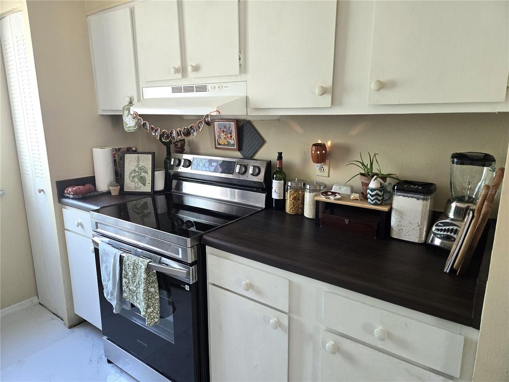 A kitchen features white cabinets, a dark countertop, and a stainless steel electric range — 6519 W NEWBERRY ROAD UNIT 204, GAINESVILLE, FL