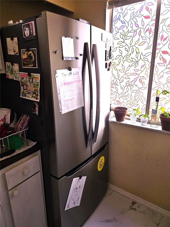 A stainless steel refrigerator stands in a kitchen next to a window with decorative film — 6519 W NEWBERRY ROAD UNIT 204, GAINESVILLE, FL