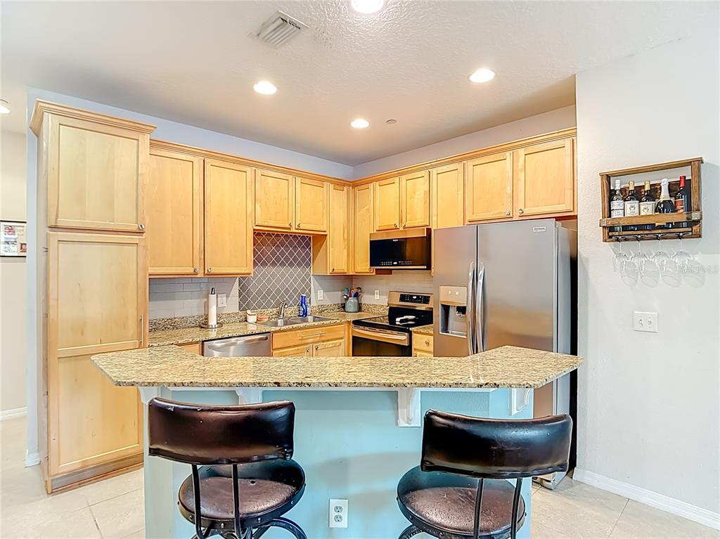 A kitchen features light wood cabinets, granite countertops, stainless steel appliances, and a breakfast bar — 2426 MIDDLETON GROVE DRIVE, BRANDON, FL