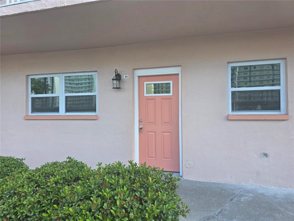 A peach-colored exterior wall features a matching front door, two windows, and a wall lamp — 6025 SHORE BOULEVARD S UNIT 105, GULFPORT, FL