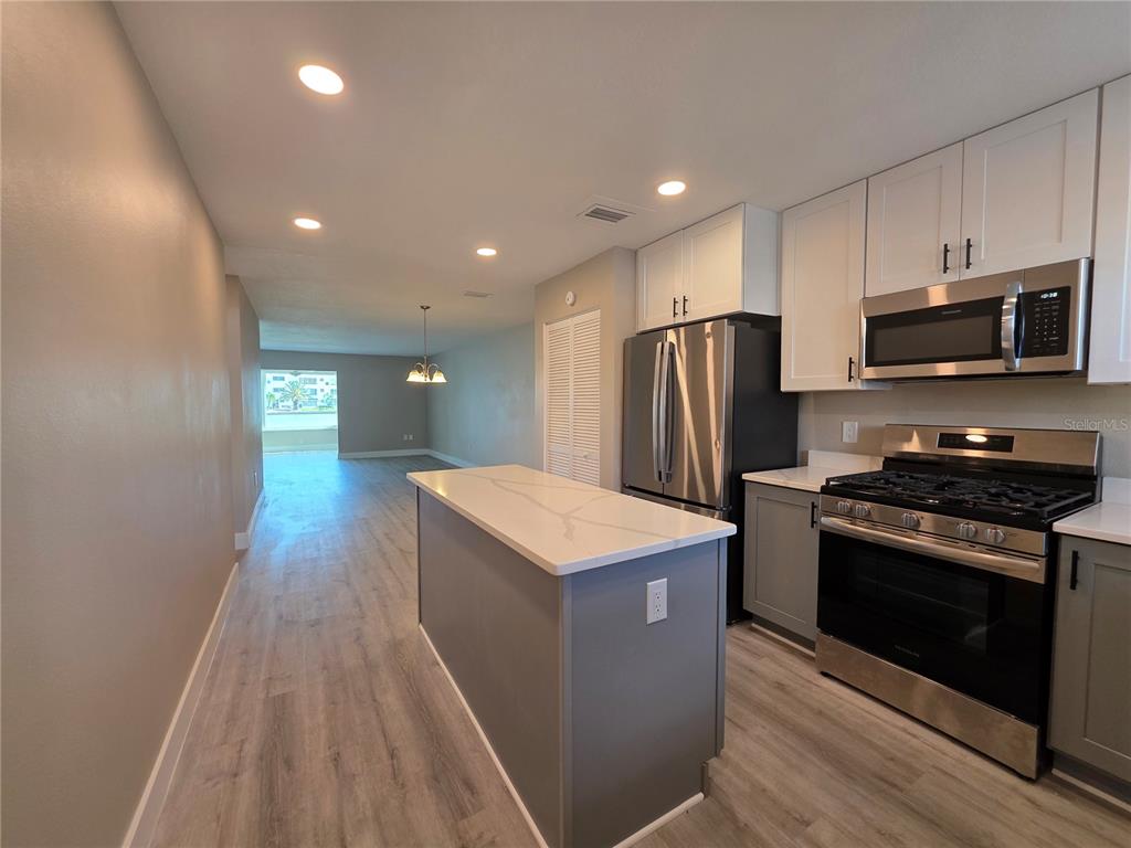 A kitchen with gray and white cabinets, a central island, and stainless steel appliances — 6025 SHORE BOULEVARD S UNIT 105, GULFPORT, FL