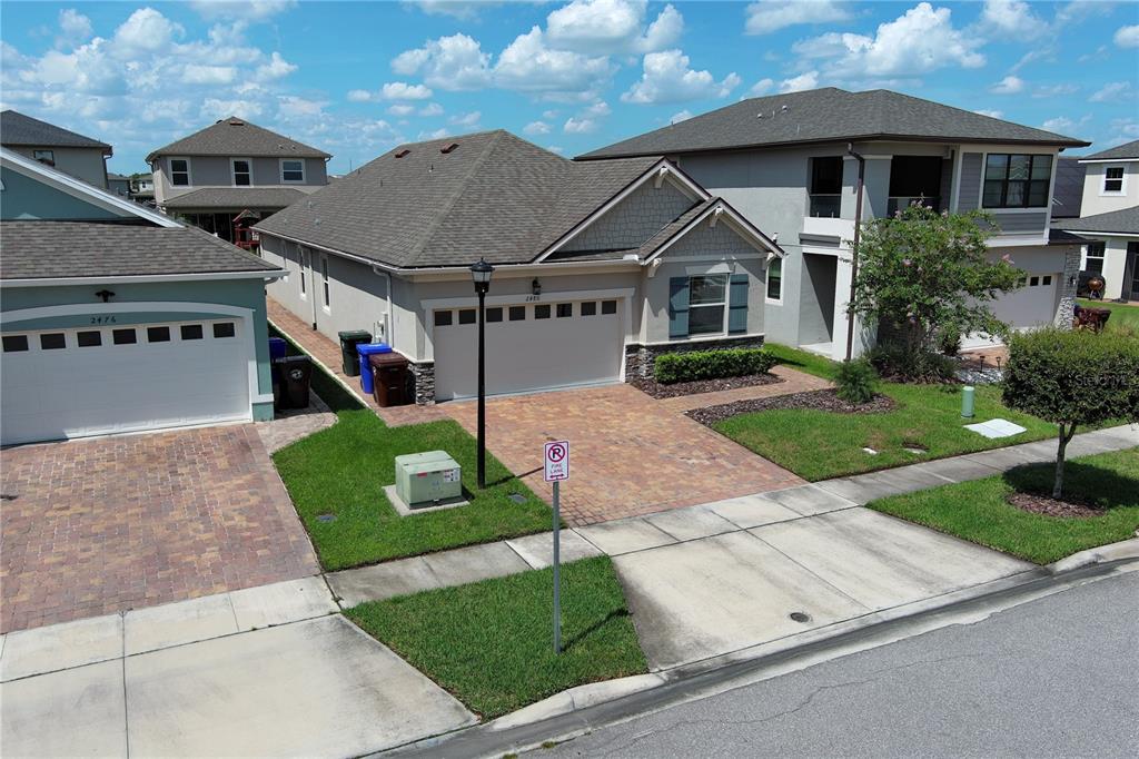 An aerial view shows a single-story suburban house with a brick driveway and garage — 2480 VARENNA LOOP, KISSIMMEE, FL