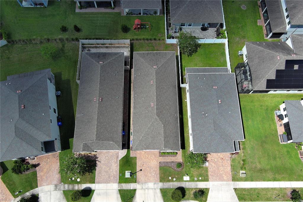 An aerial view shows three suburban houses with paved driveways and green lawns — 2480 VARENNA LOOP, KISSIMMEE, FL