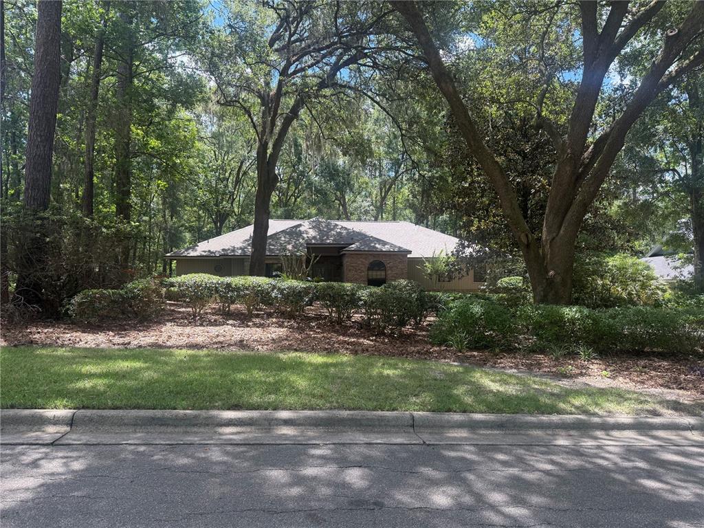 A single-story house with a stone facade and a large, leaf-covered front yard — 4427 SW 84TH WAY, GAINESVILLE, FL