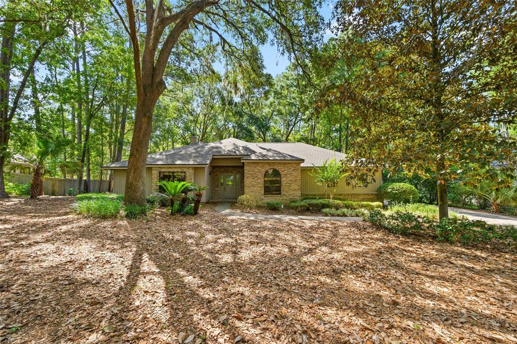 A brick walkway leads to the side entrance of a house with tan vertical siding — 4427 SW 84TH WAY, GAINESVILLE, FL