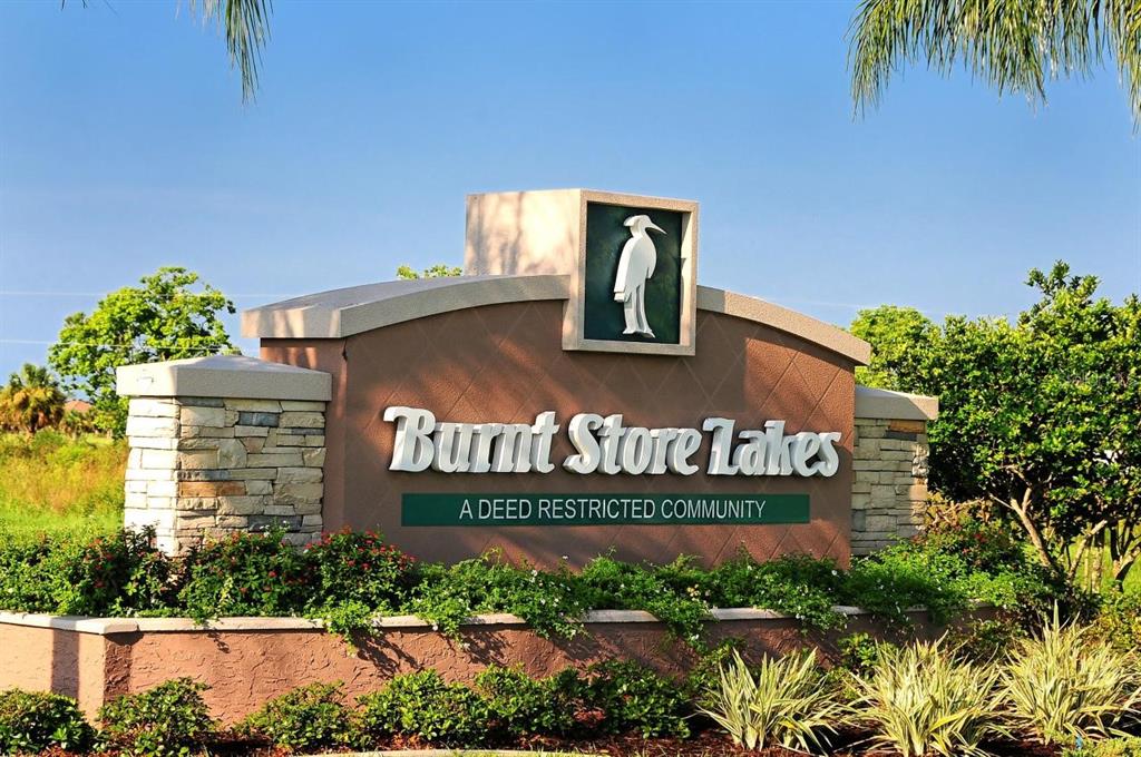 A stone and stucco monument sign marks the entrance to the Burnt Store Lakes community — 16387 RABAT WAY, PUNTA GORDA, FL