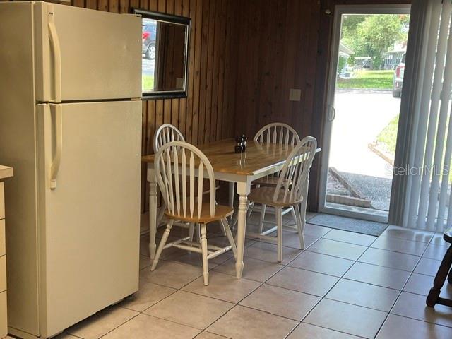 A dining area features a wooden table, four chairs, a refrigerator, and a sliding glass door — 10301 US HIGHWAY 27 UNIT 182, CLERMONT, FL