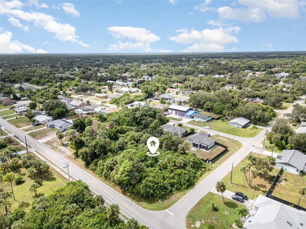 An aerial view shows a rectangular, wooded vacant lot outlined in white near a road — 18503 BARBARA AVENUE, PORT CHARLOTTE, FL