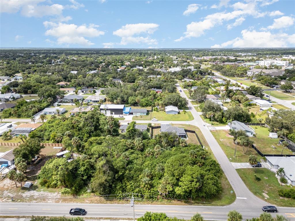 An aerial view shows a wooded lot bordered by a road and residential houses — 18503 BARBARA AVENUE, PORT CHARLOTTE, FL