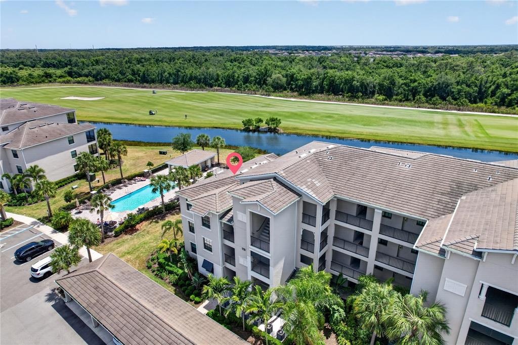 An aerial view shows a multi-story apartment building next to a pool and golf course — 17724 GAWTHROP DRIVE UNIT 301, BRADENTON, FL