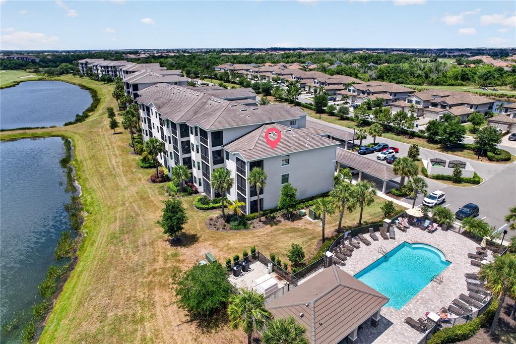 An aerial view shows a multi-story apartment building next to a lake and pool — 17724 GAWTHROP DRIVE UNIT 301, BRADENTON, FL