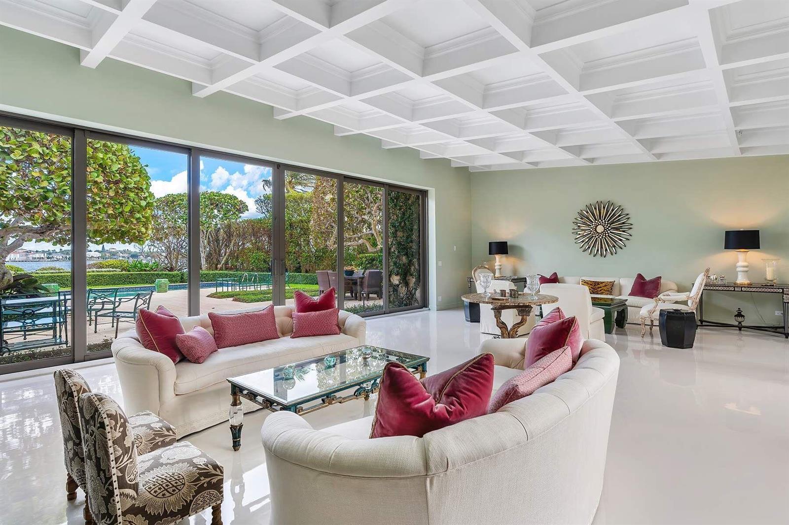 A spacious living room with a coffered ceiling, white tile floors, and large sliding glass doors — 748 Island Drive, Palm Beach FL 33480, PALM BEACH, FL