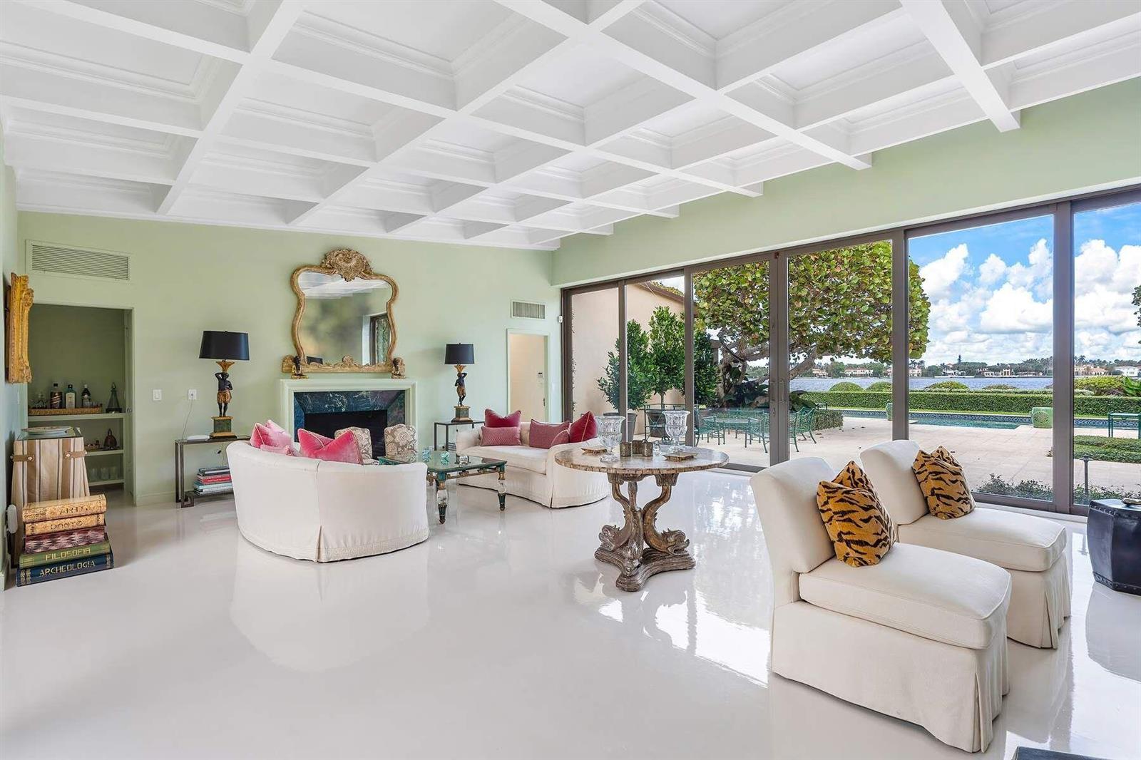 A bright living room features a coffered ceiling, white floors, fireplace, and large glass doors — 748 Island Drive, Palm Beach FL 33480, PALM BEACH, FL