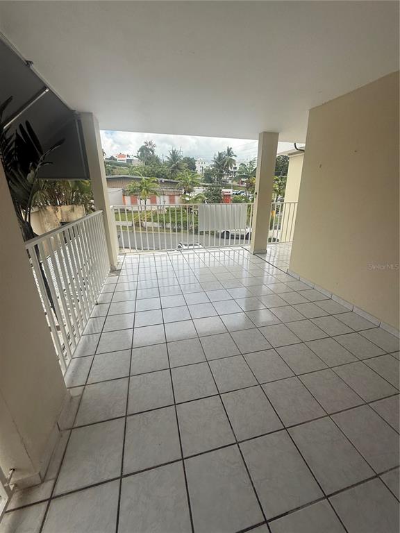 A covered balcony with white tile flooring and a white metal railing overlooking a street — 859 CALLE MARGINAL, SAN JUAN, PR