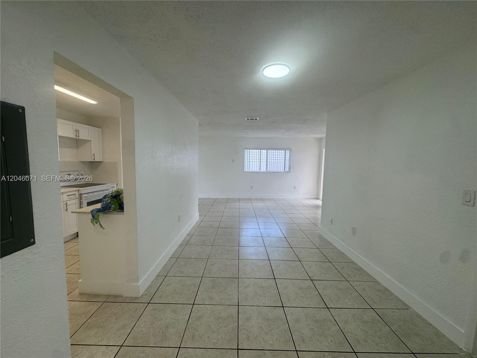 A view from a tiled room looking into a kitchen with white cabinets — 3810 SW 89th Ave # 3810, Miami FL 33165, MIAMI, FL