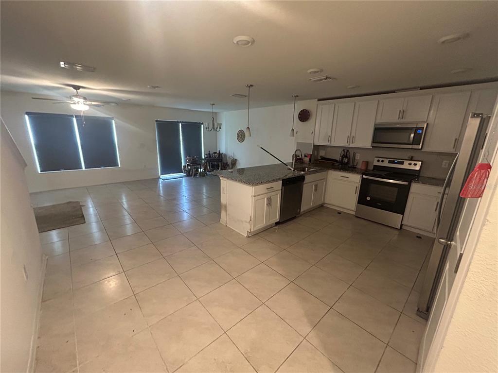 An open-concept kitchen and living area features white cabinets, granite countertops, and tile flooring — 15031 CASPIAN TERN COURT UNIT 103, NORTH FORT MYERS, FL