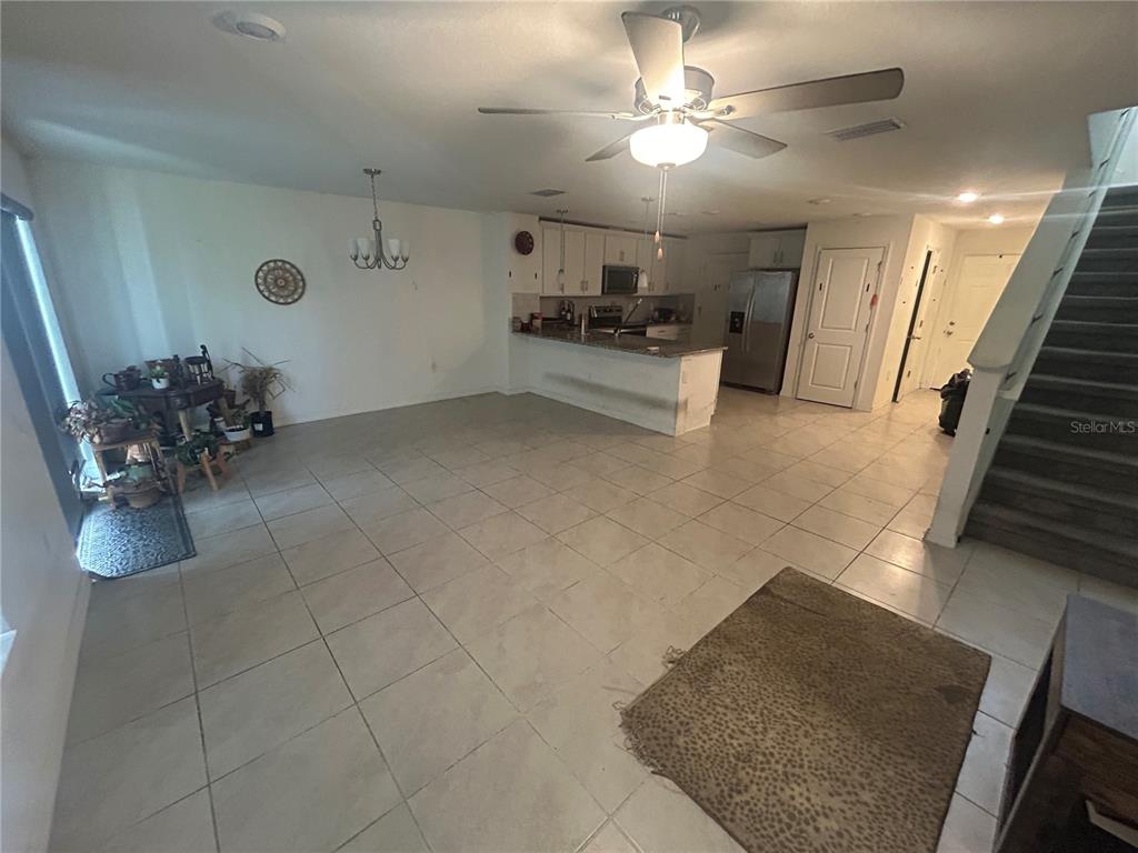 An open-concept living and dining area features tile flooring, a kitchen island, and a staircase — 15031 CASPIAN TERN COURT UNIT 103, NORTH FORT MYERS, FL