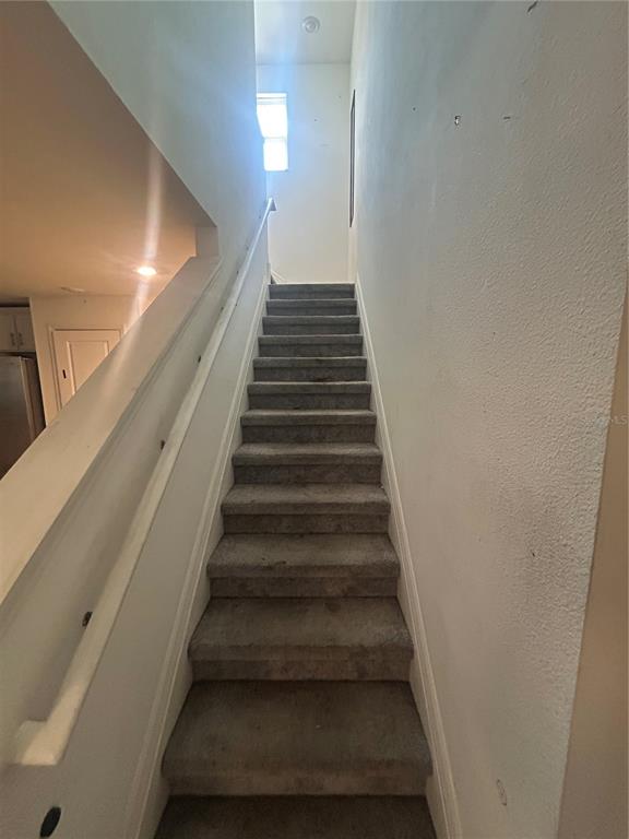 A straight staircase with gray carpet leads upward between two white walls — 15031 CASPIAN TERN COURT UNIT 103, NORTH FORT MYERS, FL