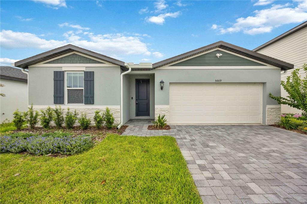 A single-story house with a light gray facade, stone base, and a paved driveway — 5009 KATRINA DRIVE, HAINES CITY, FL