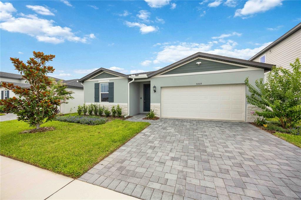 A single-story house with a light green exterior, stone accents, and a paved driveway — 5009 KATRINA DRIVE, HAINES CITY, FL
